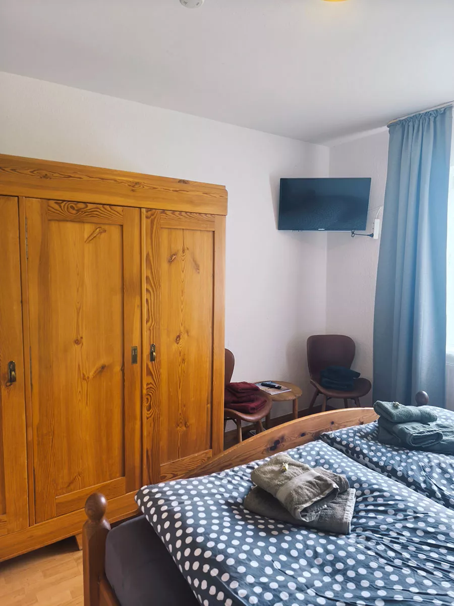 Ferienhaus Deichsonne – Schlafzimmer mit Kleiderschrank, Sitzecke und TV