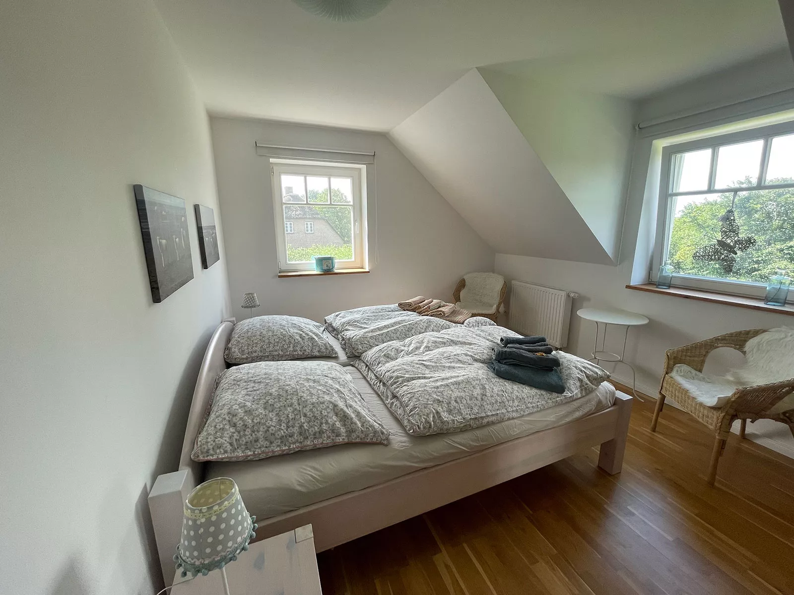 Ferienhaus Deichstern – Schlafzimmer mit Doppelbett, Sitzplatz und Ausblick ins Grüne